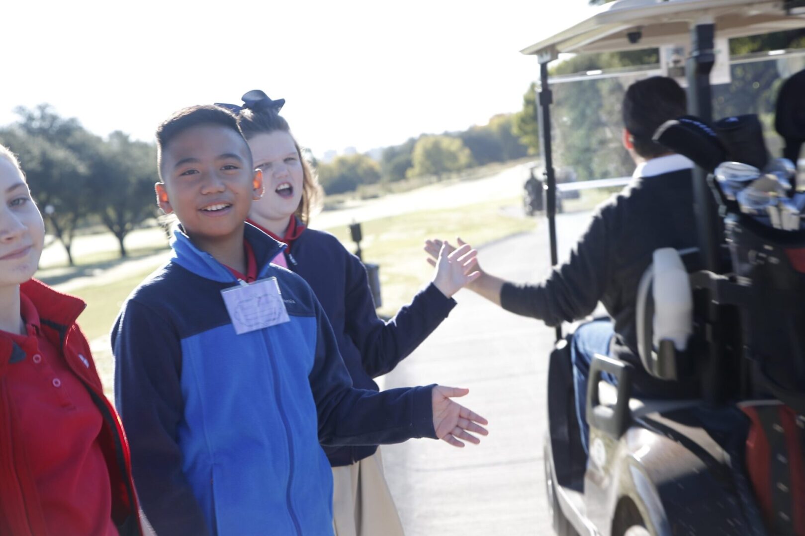 Two children are getting off a golf cart.