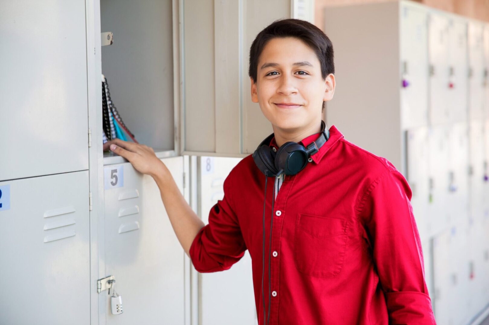 A boy in red shirt holding up a laptop.