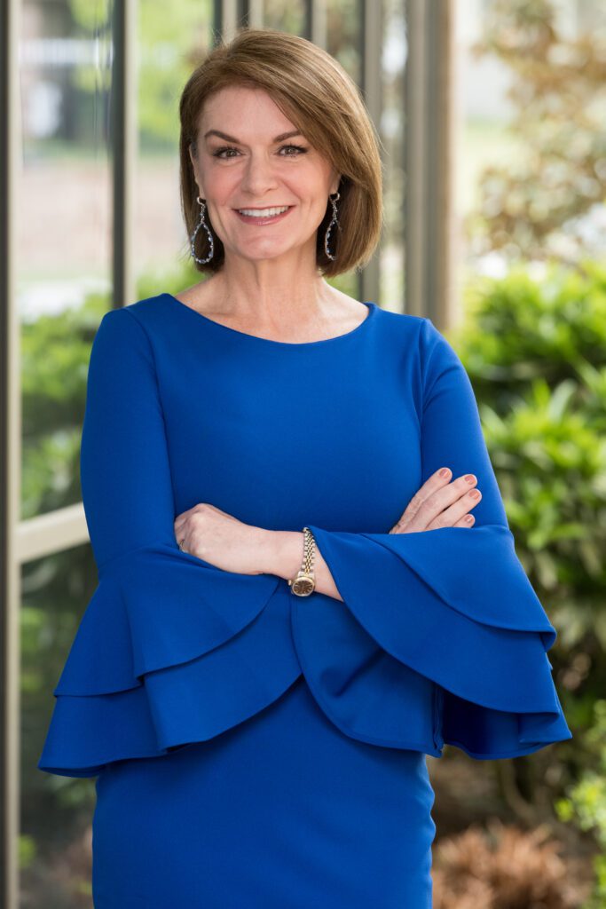 A woman in blue dress with arms crossed.
