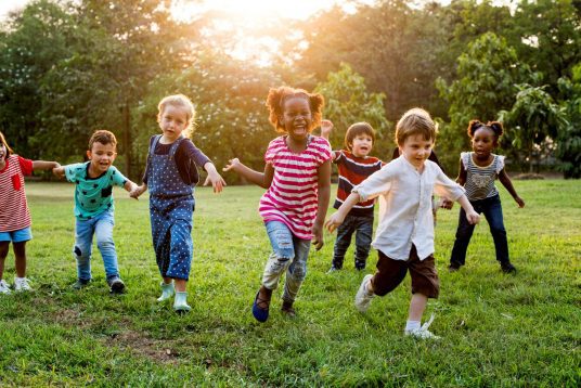 A group of children running in the grass.