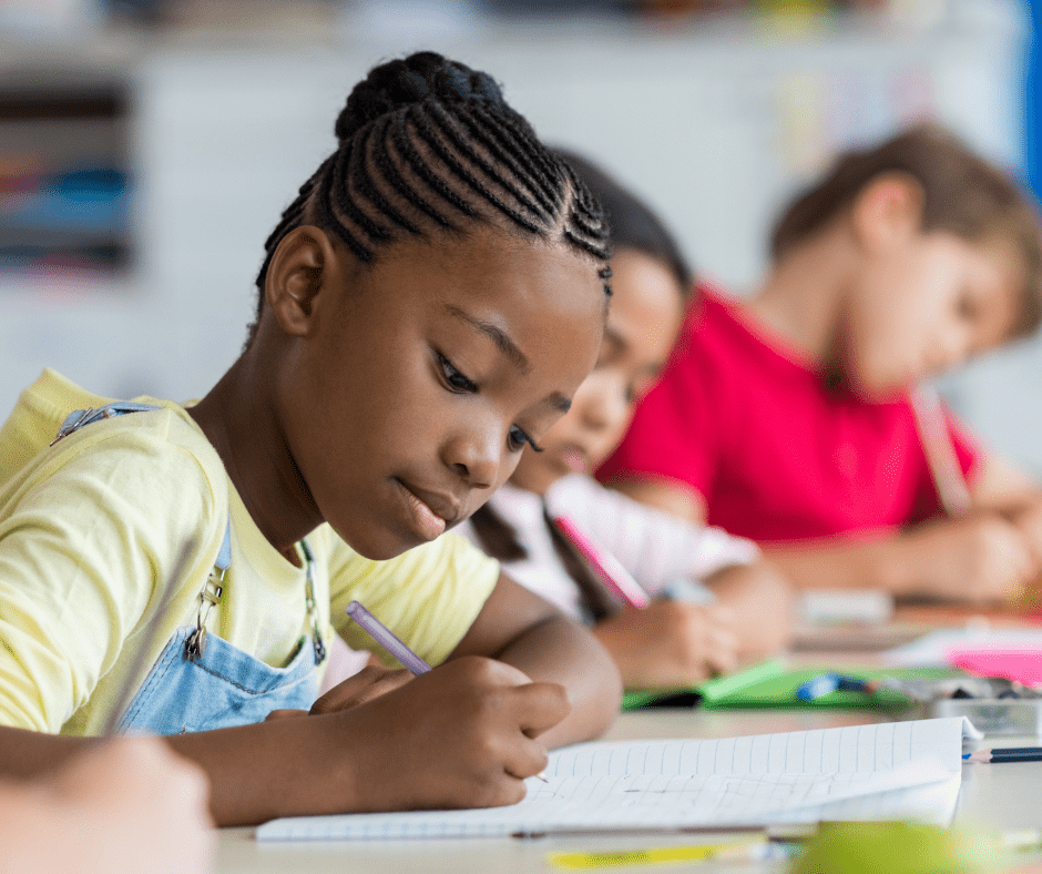 A group of children sitting at a table writing.