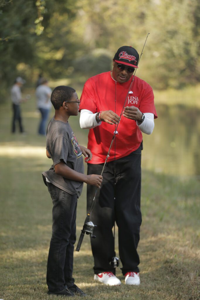 A man and boy fishing in the grass.