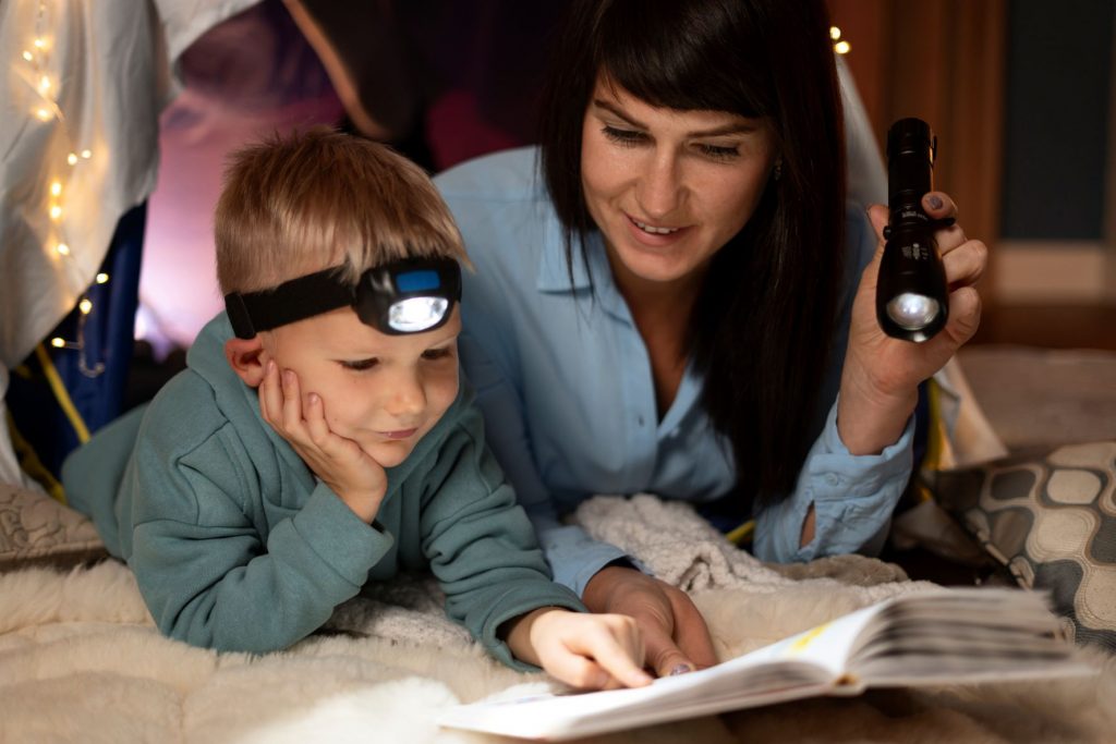 woman reading with kid together with flashlights