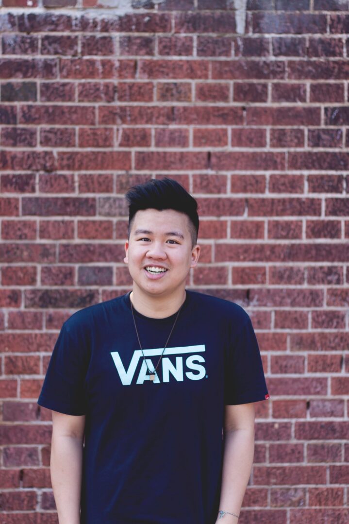 A man standing in front of a brick wall.