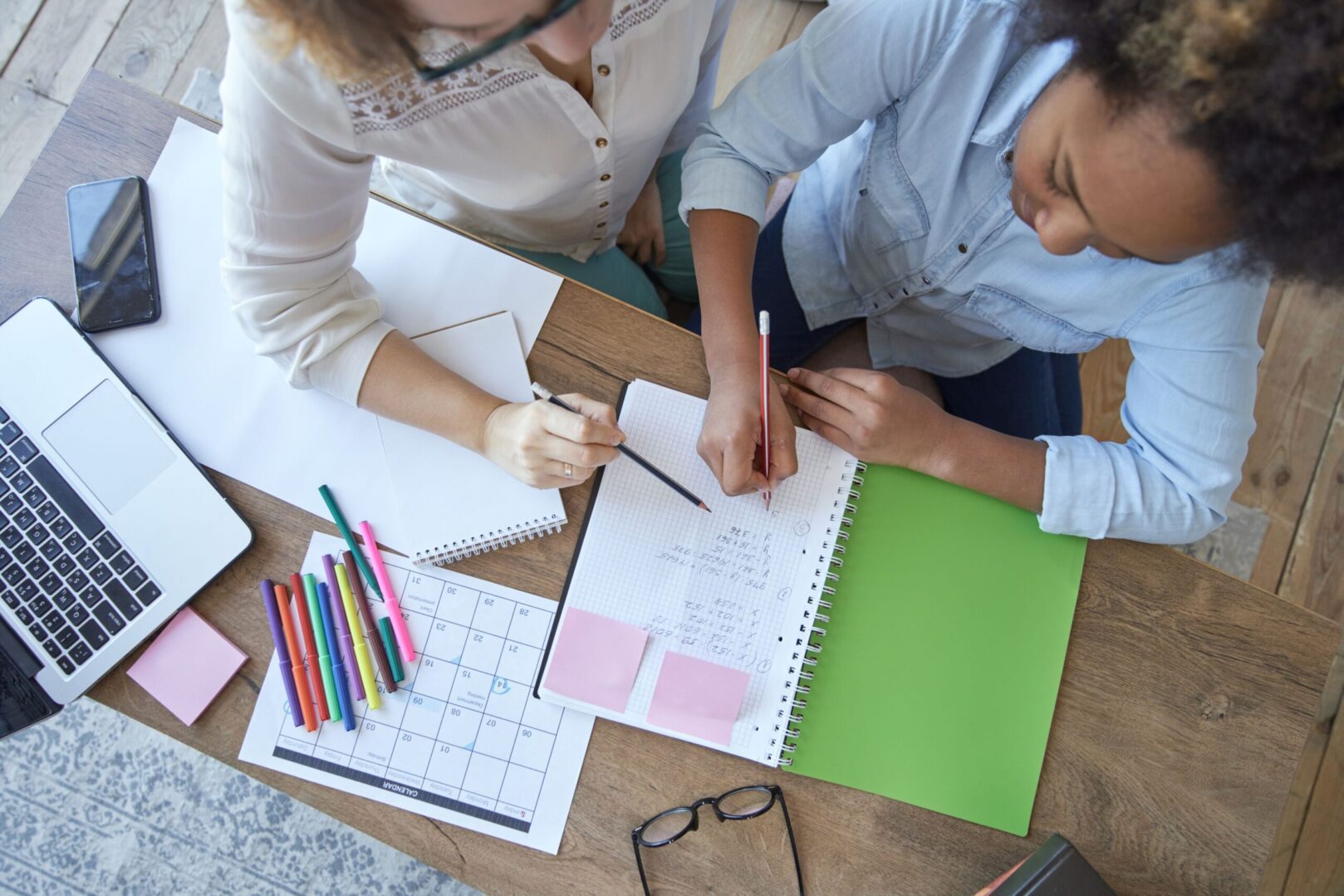 Two people sitting at a table with pens and paper