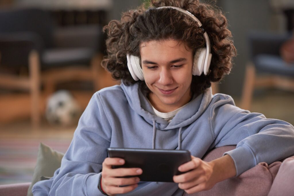 A person with headphones on looking at an ipad.
