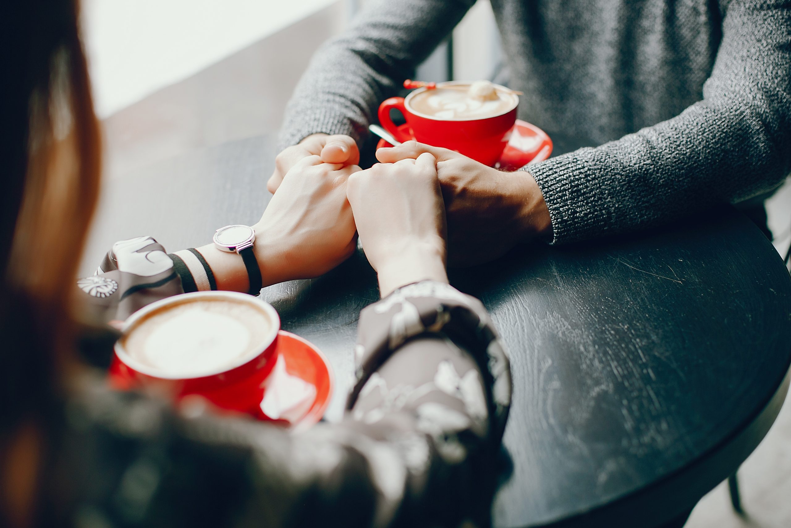 two people drinking a coffee out of red cups and holding hands