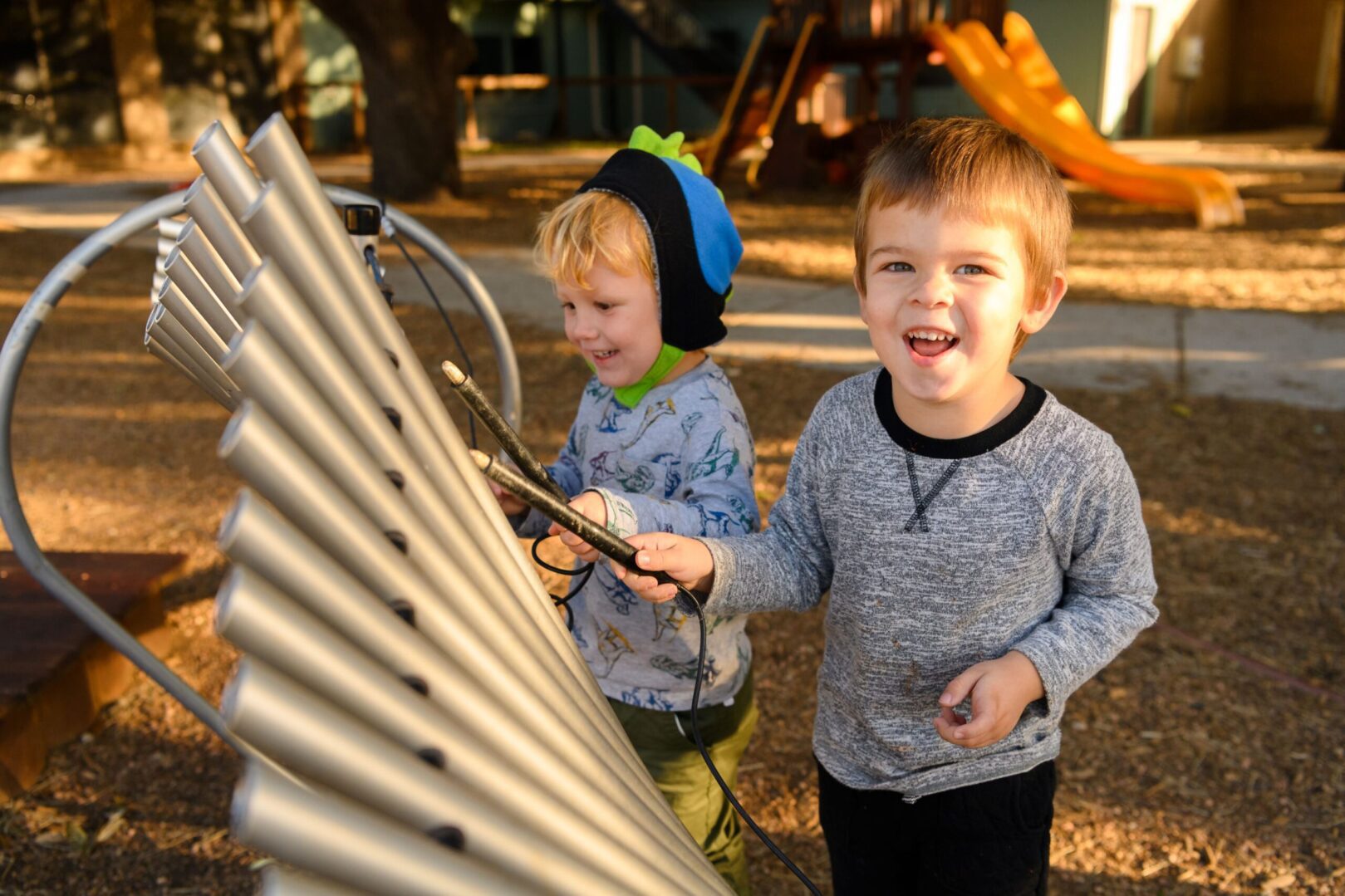 Two young boys playing with a bunch of pipes