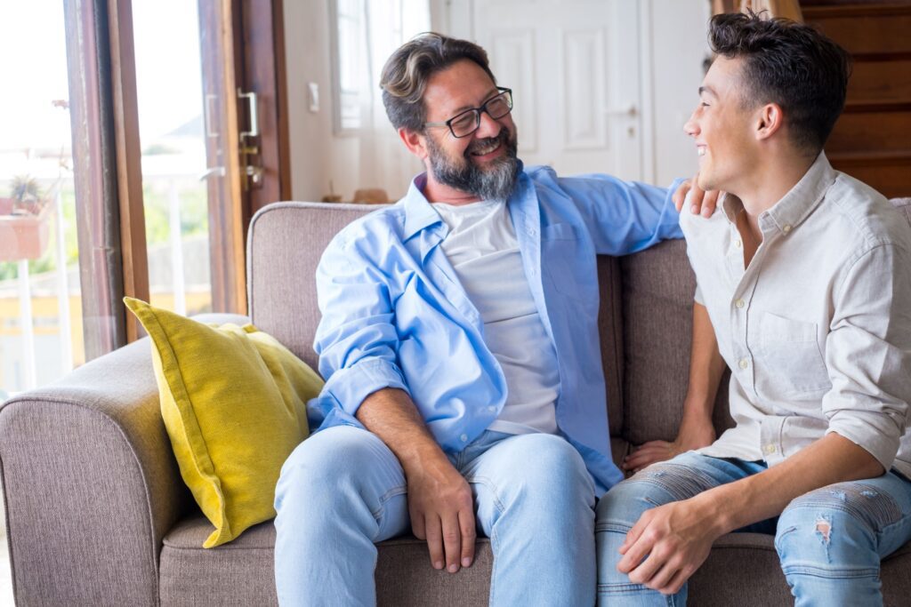 A man and boy sitting on the couch talking.
