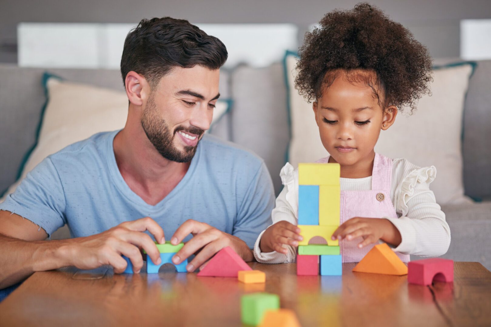 father and child playing with colorful blocks together at a table